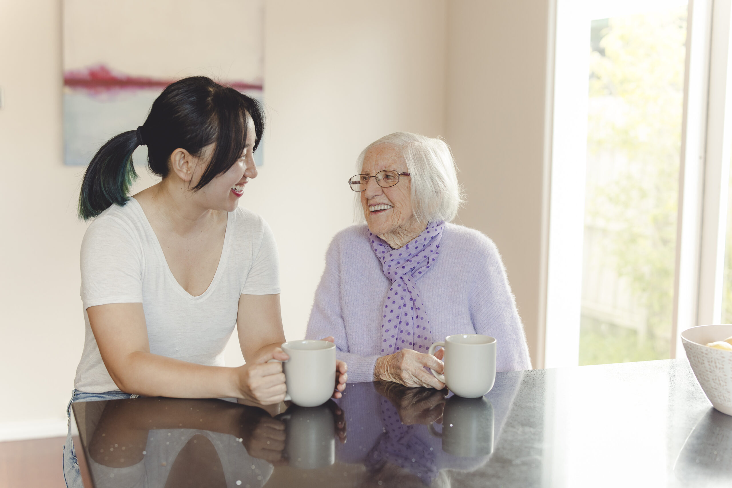 Who we care for - A young woman and a senior woman having coffee together