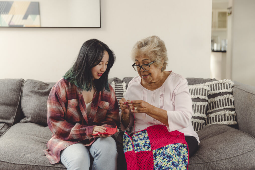 A young woman is seated on the couch beside a senior woman