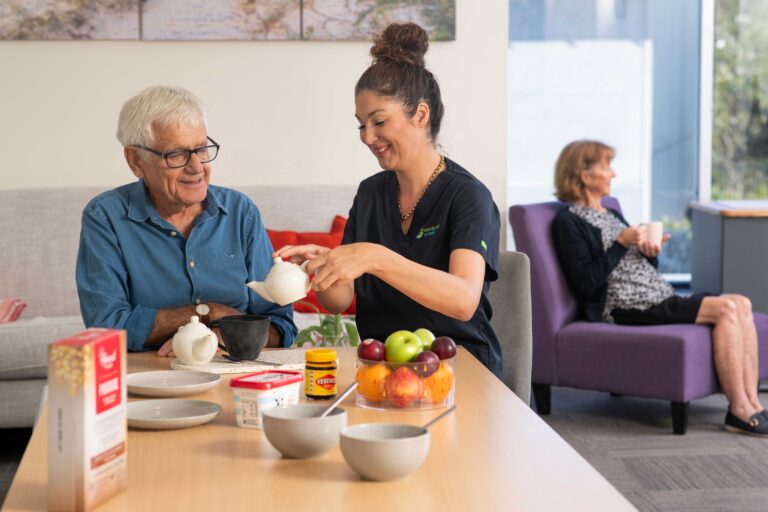 A Care For You at Home staff member pouring water from a teapot for a senior man