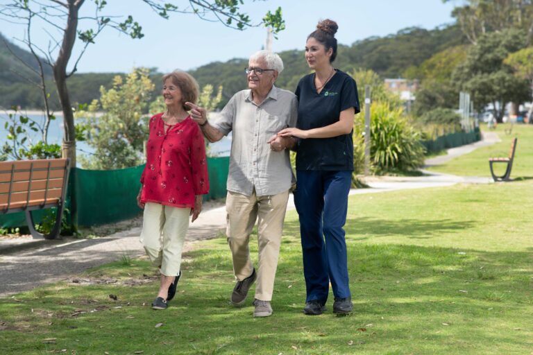A senior man and woman walking outdoors with a Care For You at Home staff member