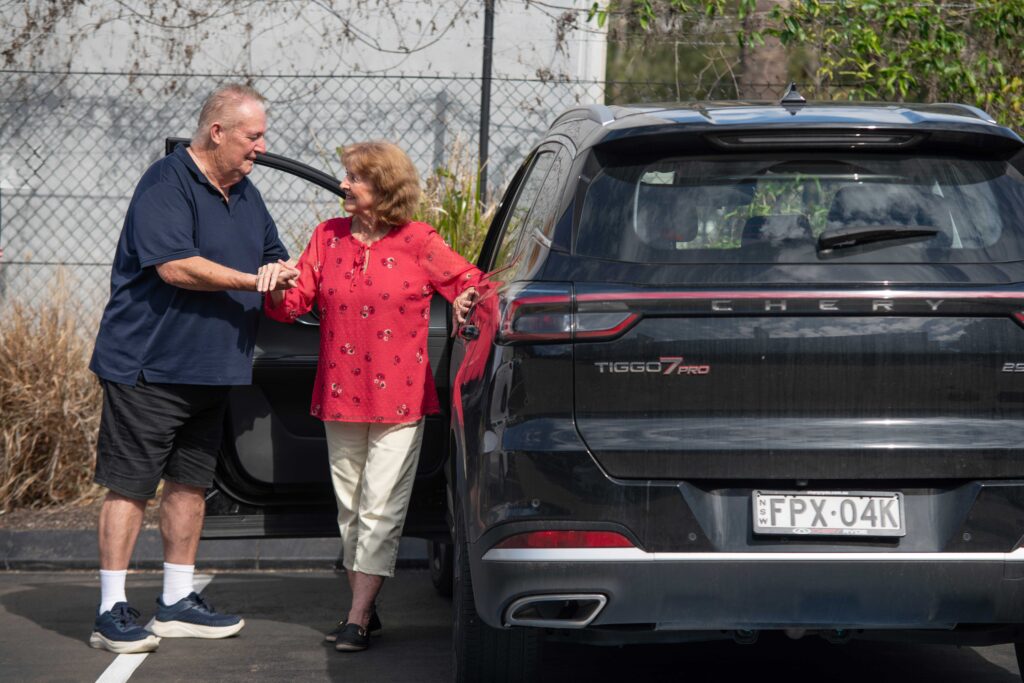 A man helping a senior woman out of a car